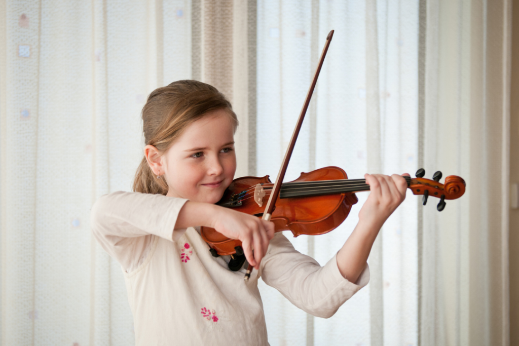 Focused young girl playing the violin with confidence and good posture, showing early signs of musical talent and coordination.
