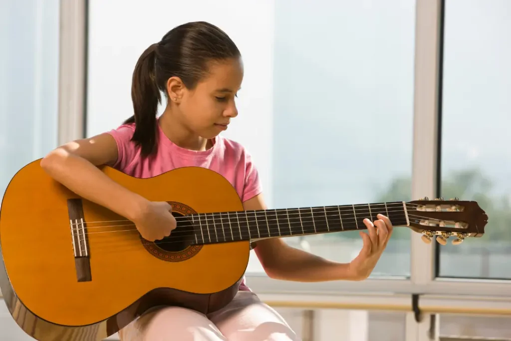 A beginner practicing acoustic guitar at home, holding the instrument correctly with a tuner nearby, learning basic chords for the first time