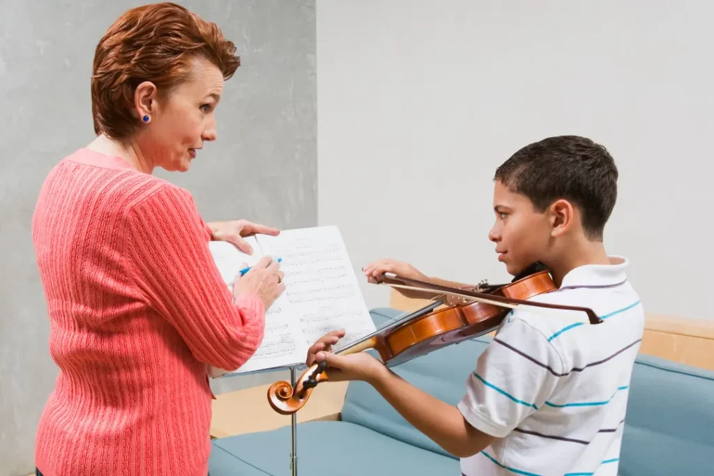 Beginner violin student holding a properly sized violin during a first lesson, with an instructor teaching basic posture. 