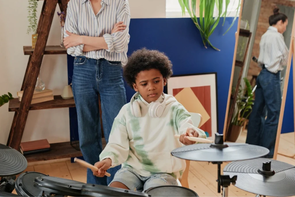 Beginner drummer practicing on an electronic drum kit at home, following online lessons with focused posture and proper stick technique