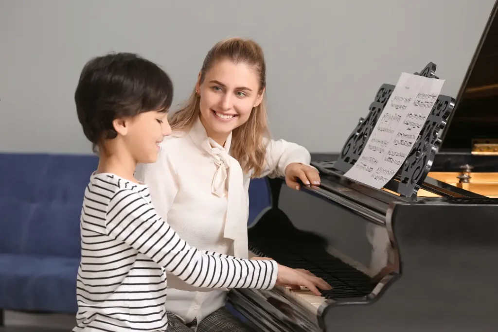 A young child happily plays piano with a music teacher, showcasing the joy of learning music. 