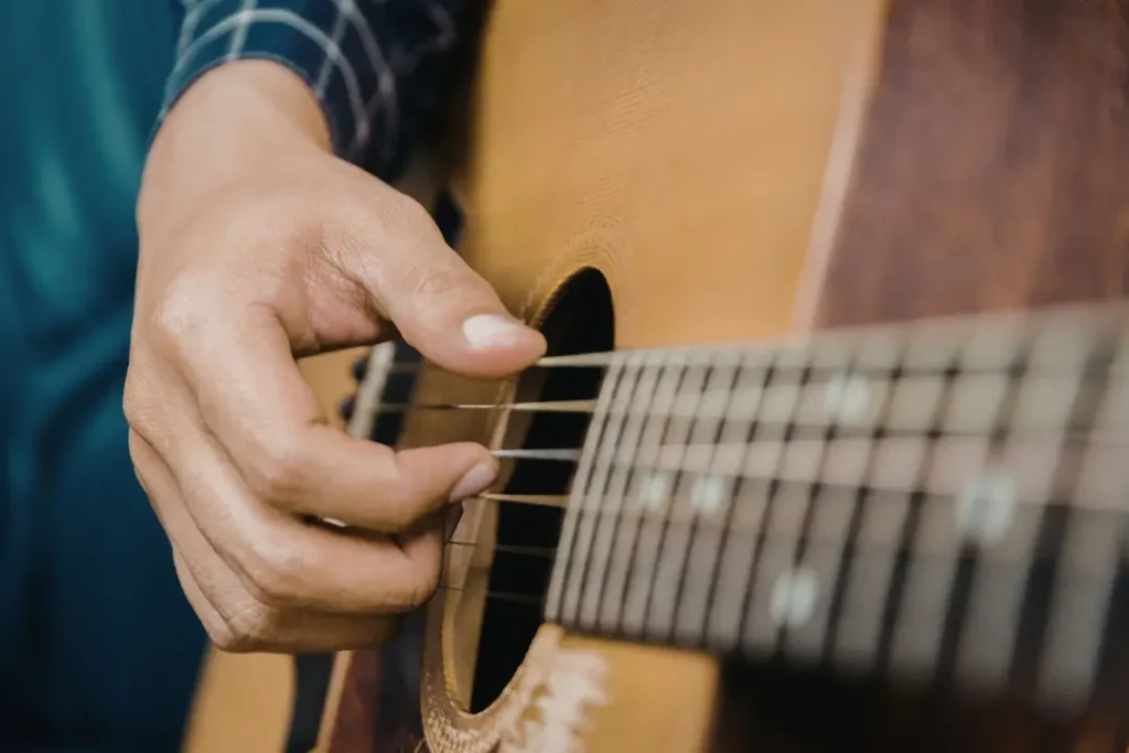 An acoustic guitar displayed alongside various music books and a metronome, symbolizing essential tools for music education. 