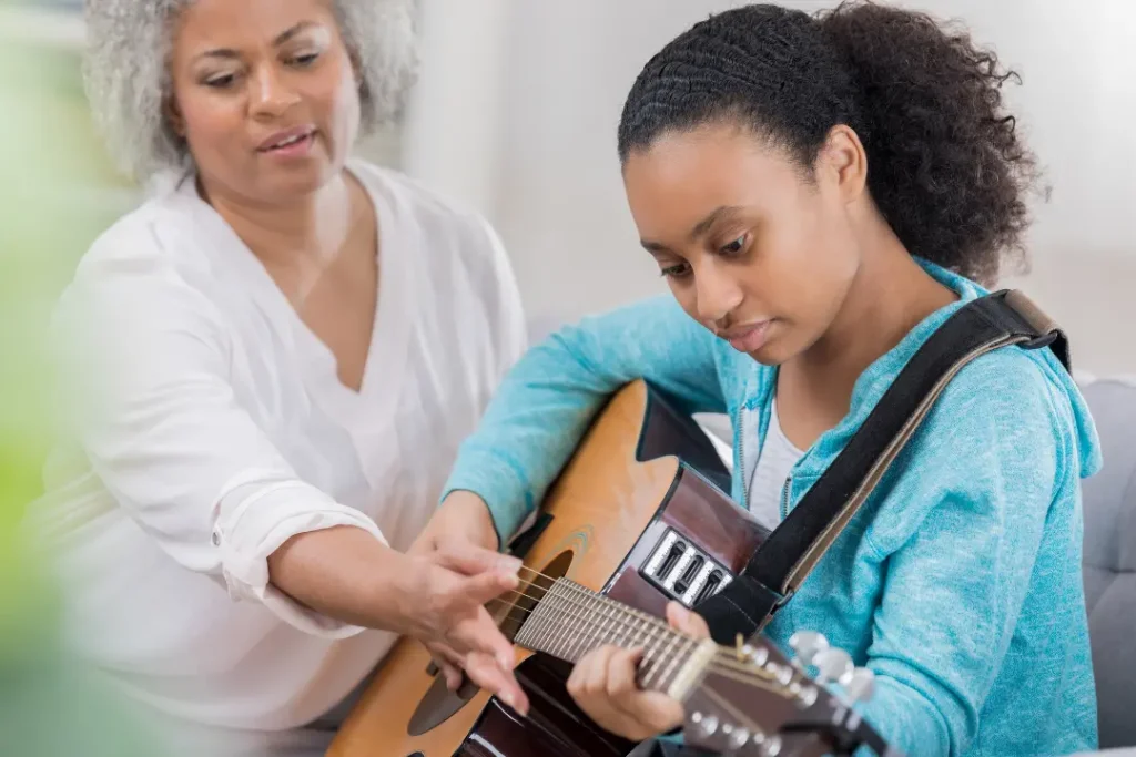 Beginner guitar student practicing basic chord changes during a private guitar lesson