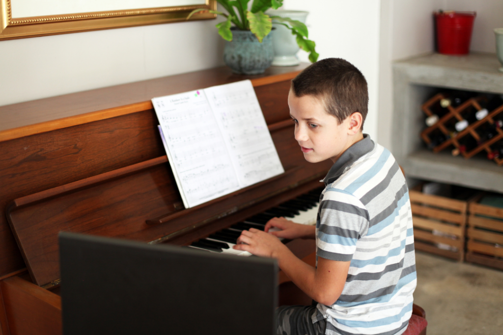 Beginner piano student practicing proper finger placement and posture during a lesson