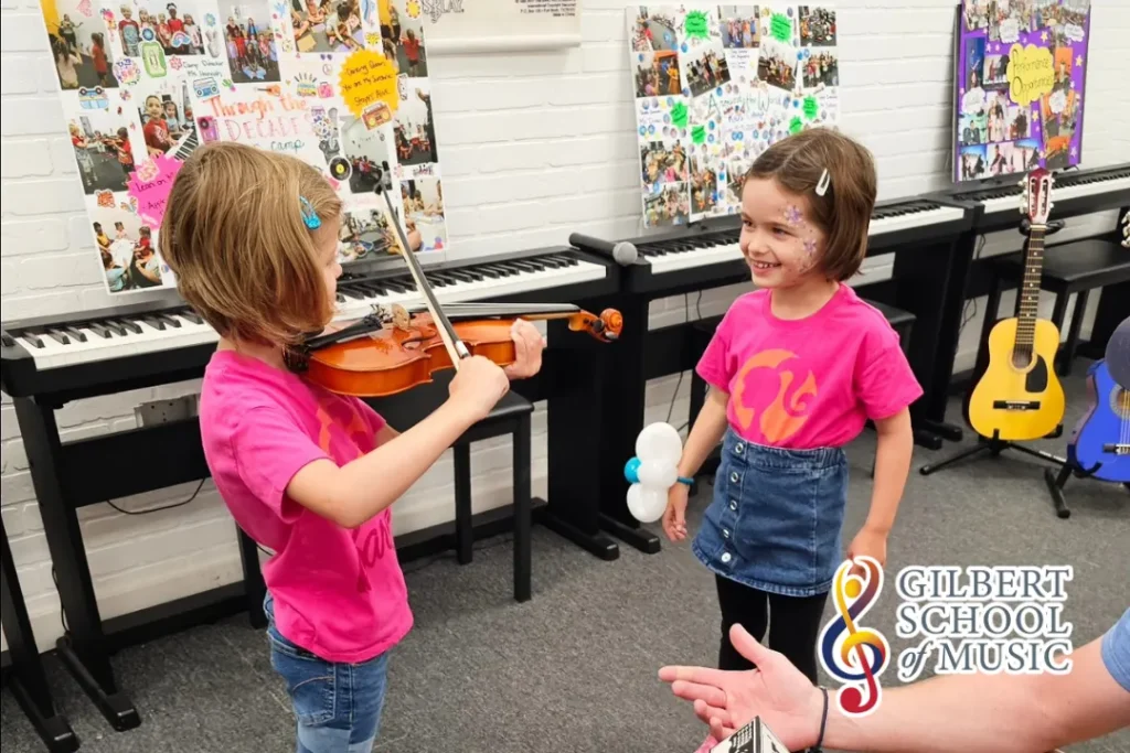 Student practicing violin with a Gilbert School of Music instructor, learning proper posture and bow technique