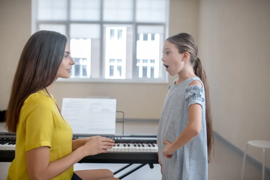 Instructor teaching proper singing posture, breath support, and vocal tract alignment for beginner singers.
