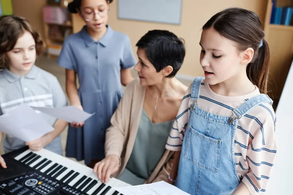Students singing while instructor is playing piano in a group voice lesson setting
